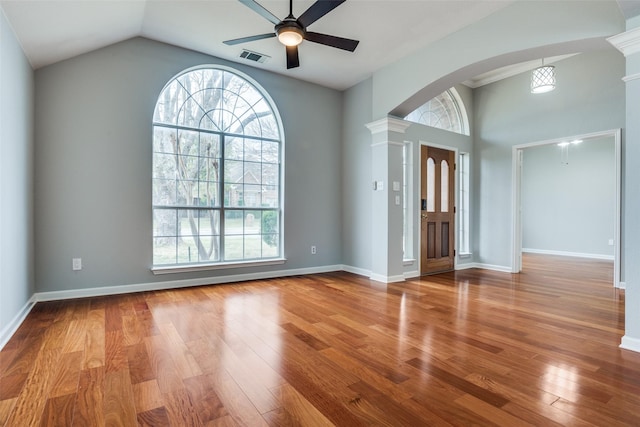 entryway featuring arched walkways, wood finished floors, a ceiling fan, baseboards, and decorative columns