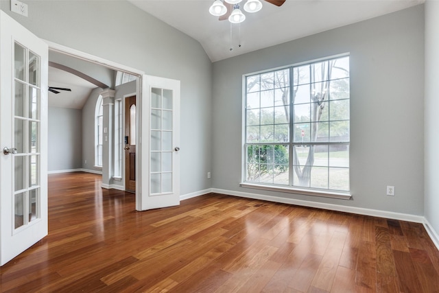 spare room with arched walkways, ceiling fan, wood finished floors, vaulted ceiling, and french doors