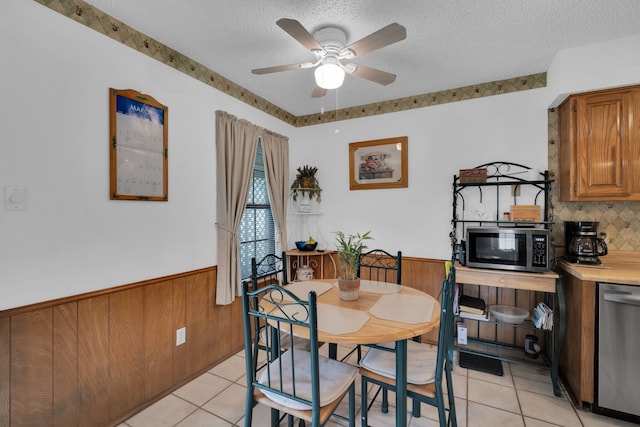 dining room with wainscoting, a textured ceiling, and light tile patterned floors