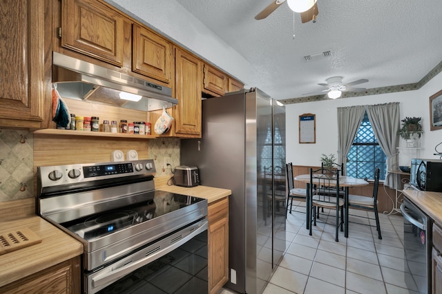 kitchen with under cabinet range hood, stainless steel appliances, visible vents, light countertops, and brown cabinets