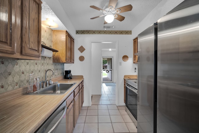 kitchen featuring light tile patterned floors, a sink, visible vents, appliances with stainless steel finishes, and decorative backsplash