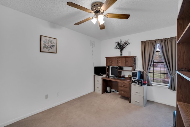 office space featuring a ceiling fan, light carpet, a textured ceiling, and baseboards