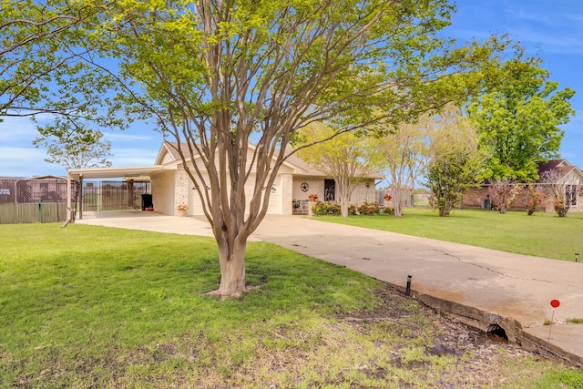 view of front of property with a front yard, concrete driveway, brick siding, and fence