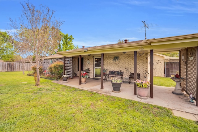 back of property featuring brick siding, a patio area, fence, and a yard