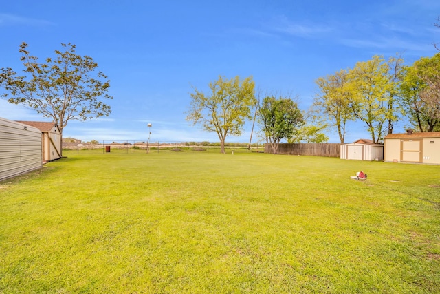 view of yard featuring an outbuilding, fence, and a storage shed