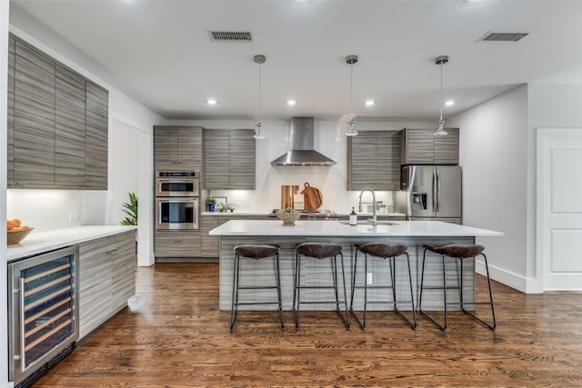 kitchen with beverage cooler, wall chimney exhaust hood, modern cabinets, a kitchen breakfast bar, and stainless steel appliances