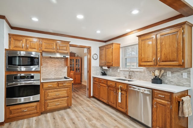 kitchen featuring brown cabinets, under cabinet range hood, stainless steel appliances, and a sink