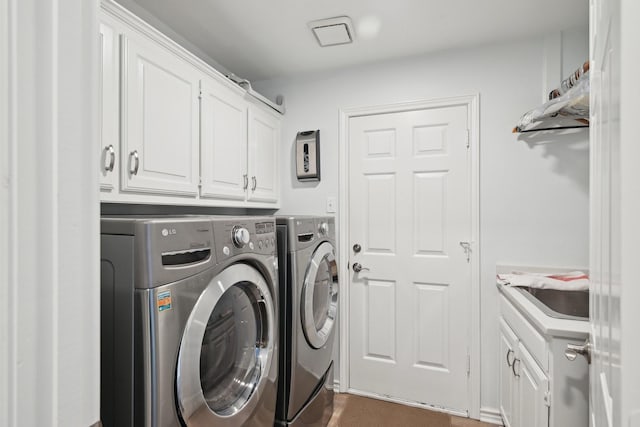 clothes washing area with washing machine and dryer and cabinet space