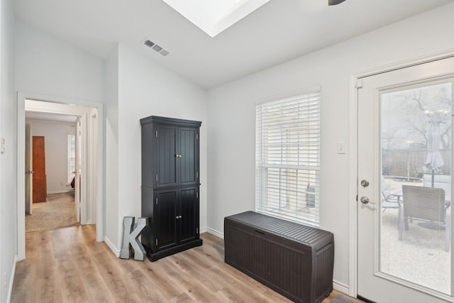 entryway featuring light wood-style floors, baseboards, visible vents, and lofted ceiling with skylight