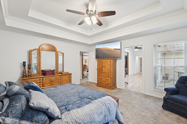 carpeted bedroom featuring a ceiling fan, a raised ceiling, and crown molding