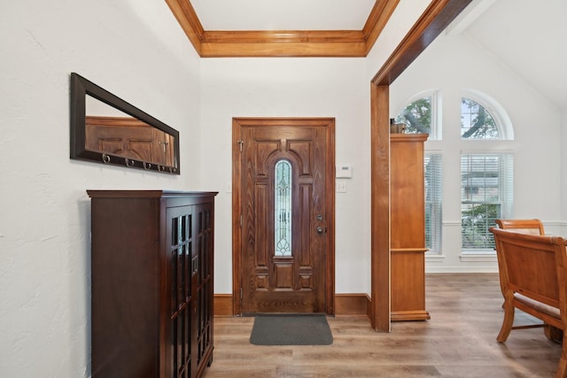 entrance foyer featuring plenty of natural light, crown molding, vaulted ceiling, and wood finished floors