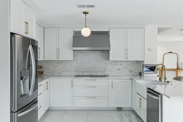 kitchen with a peninsula, white cabinetry, range hood, appliances with stainless steel finishes, and light stone countertops