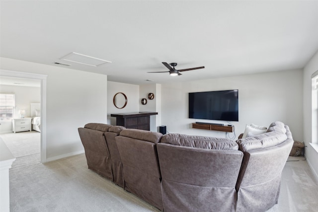 living area with attic access, visible vents, baseboards, a ceiling fan, and light colored carpet