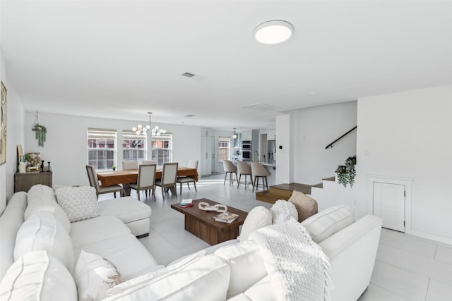 living room with stairway, light tile patterned floors, visible vents, and an inviting chandelier