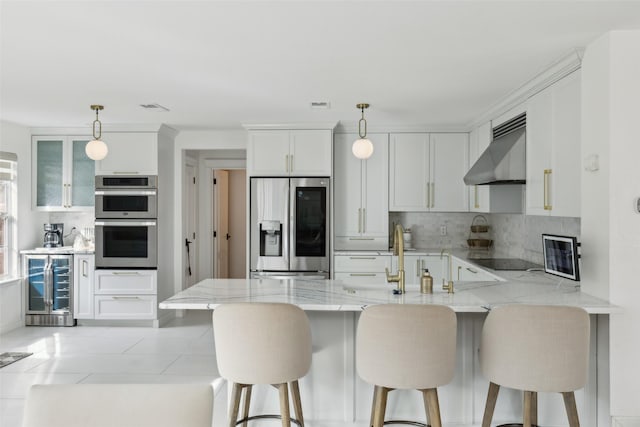 kitchen featuring stainless steel appliances, light stone countertops, beverage cooler, a peninsula, and wall chimney exhaust hood