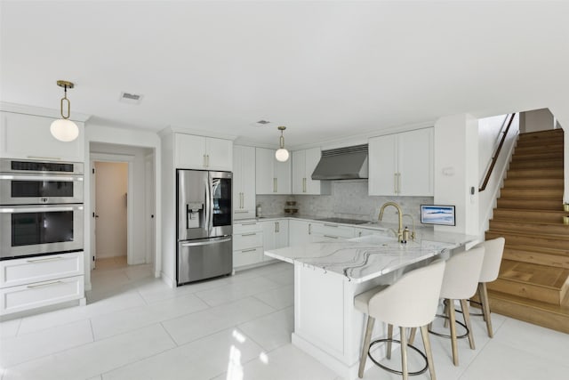 kitchen featuring visible vents, appliances with stainless steel finishes, a peninsula, under cabinet range hood, and a sink