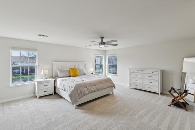 bedroom featuring a ceiling fan, visible vents, light carpet, and baseboards