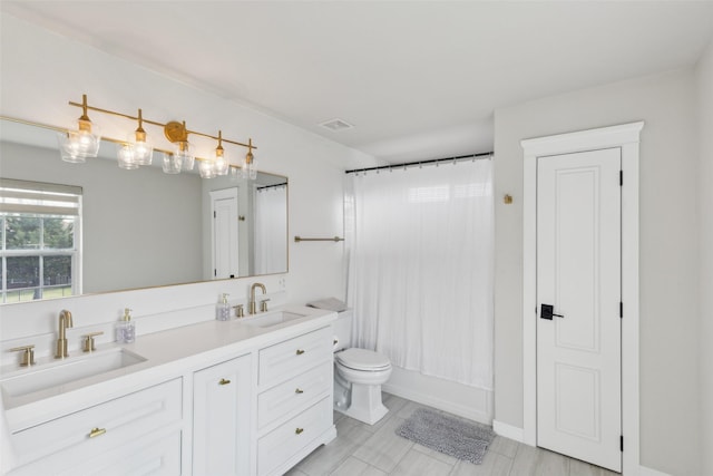 bathroom with double vanity, shower / bath combo, toilet, and a sink