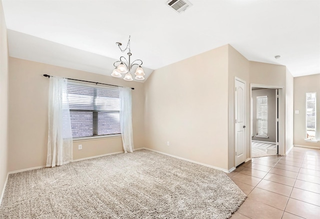 spare room featuring light tile patterned floors, visible vents, lofted ceiling, and a healthy amount of sunlight