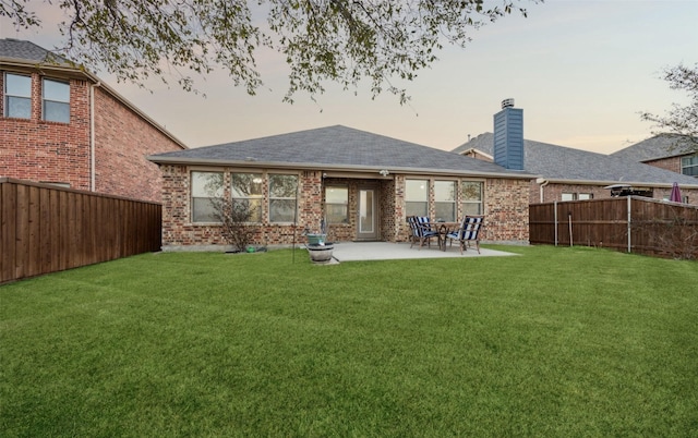 back of house featuring a lawn, a fenced backyard, and brick siding