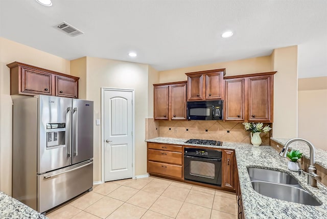 kitchen with light tile patterned floors, backsplash, a sink, a peninsula, and black appliances