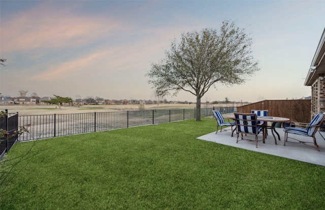 yard at dusk with a fenced backyard and a patio area