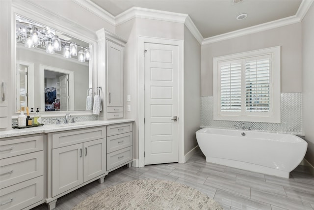 full bath with a wainscoted wall, vanity, tile walls, ornamental molding, and a soaking tub