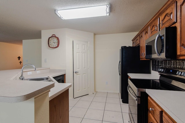 kitchen with stainless steel appliances, brown cabinetry, a sink, and light countertops