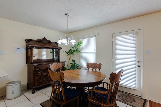 dining area with a textured ceiling, light tile patterned floors, and an inviting chandelier