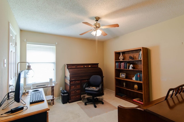 home office with light carpet, baseboards, a ceiling fan, and a textured ceiling