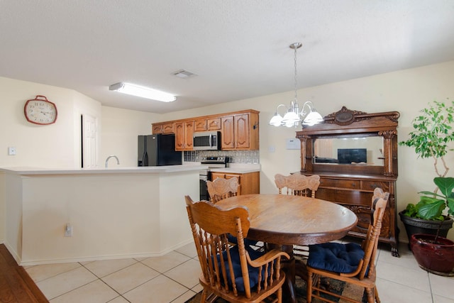 dining area featuring light tile patterned floors, baseboards, visible vents, and a notable chandelier