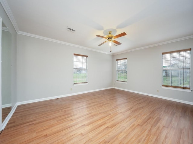 empty room featuring light wood-type flooring, visible vents, crown molding, and baseboards