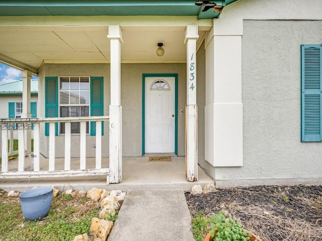 view of exterior entry with covered porch and stucco siding