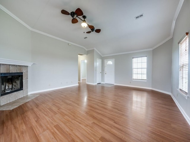 unfurnished living room featuring crown molding, visible vents, a tiled fireplace, and wood finished floors