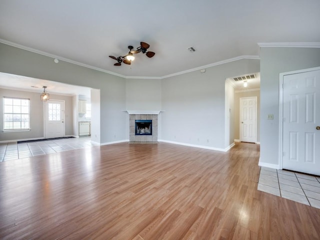 unfurnished living room featuring light wood-style floors, visible vents, ceiling fan, and a tiled fireplace