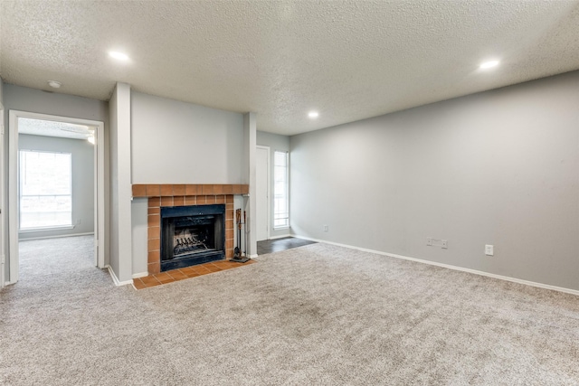 unfurnished living room featuring carpet floors, baseboards, a tiled fireplace, and recessed lighting