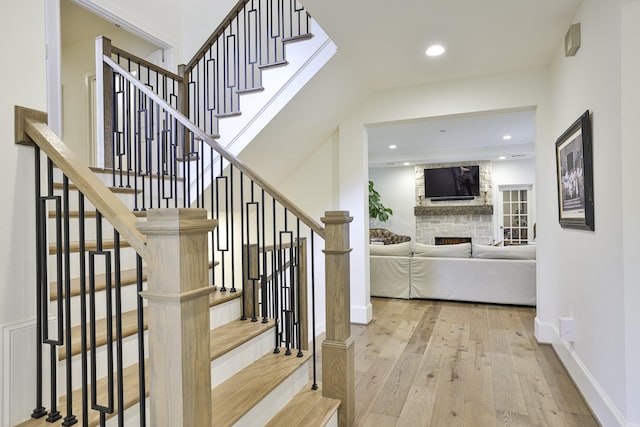 stairway with hardwood / wood-style floors, a fireplace, recessed lighting, and baseboards