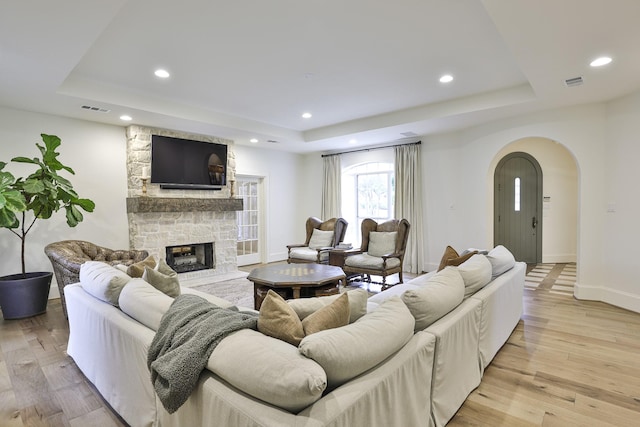 living area featuring light wood-style floors, visible vents, and a tray ceiling