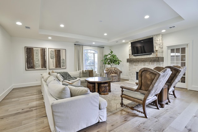 living area with a raised ceiling, visible vents, and light wood-style flooring