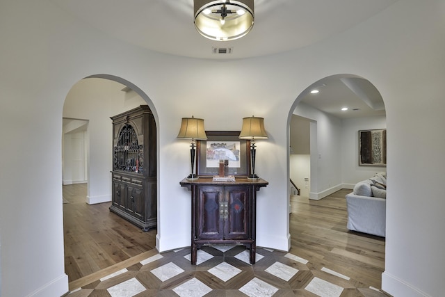 corridor featuring dark wood-style flooring, visible vents, and baseboards