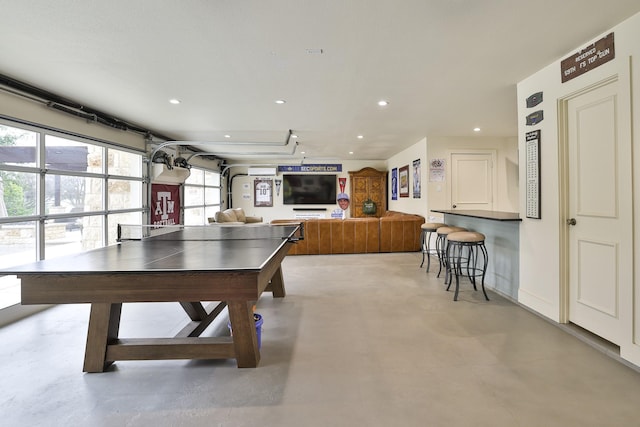 game room with a garage, recessed lighting, baseboards, and concrete flooring