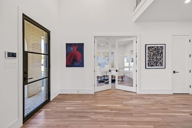 foyer entrance featuring french doors, light wood-style flooring, and baseboards