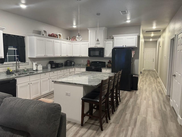 kitchen with white cabinets, visible vents, black appliances, a sink, and light wood finished floors