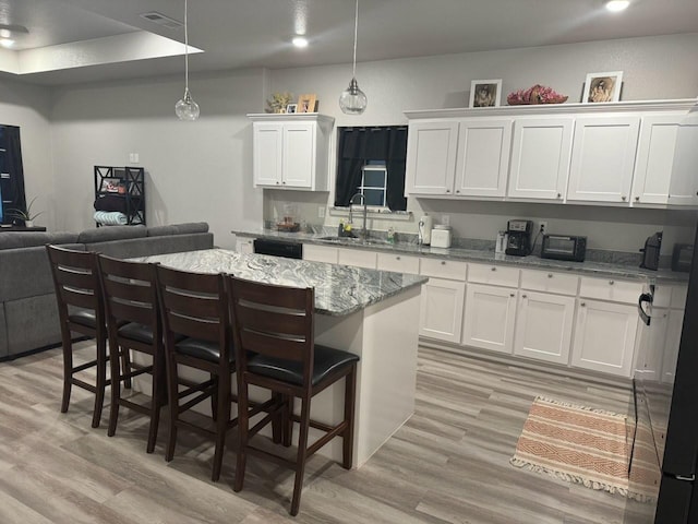 kitchen with a center island, a sink, open floor plan, light wood-type flooring, and white cabinetry