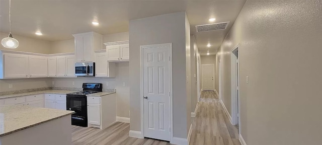 kitchen featuring stainless steel microwave, black range with gas stovetop, white cabinets, visible vents, and light wood finished floors