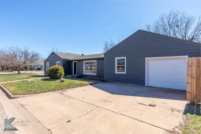 ranch-style house featuring concrete driveway, an attached garage, and a front lawn