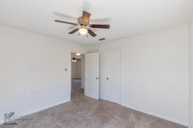 spare room with carpet floors, visible vents, and baseboards