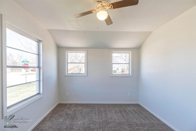 carpeted spare room featuring vaulted ceiling, baseboards, and ceiling fan