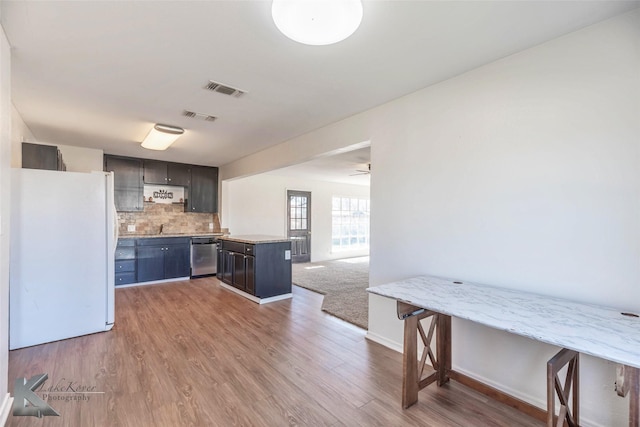 kitchen featuring visible vents, decorative backsplash, dishwasher, and freestanding refrigerator