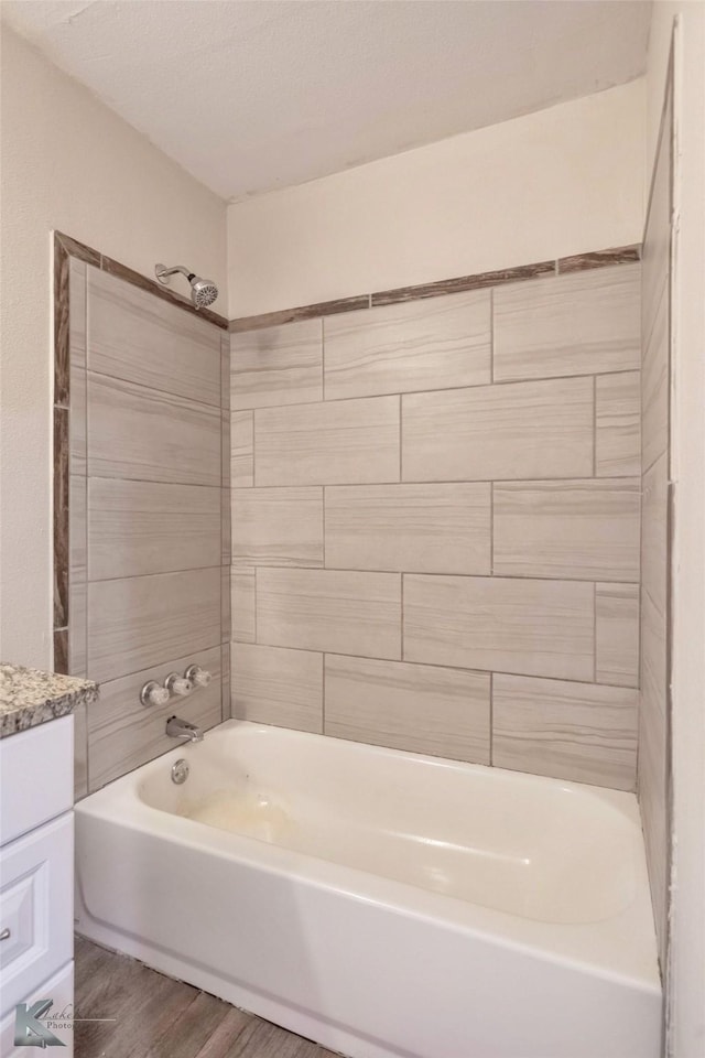 full bathroom with  shower combination, vanity, a textured ceiling, and wood finished floors